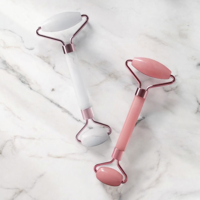 Rouleaux de massage visage VELURA en quartz rose et quartz blanc sur fond marbre
